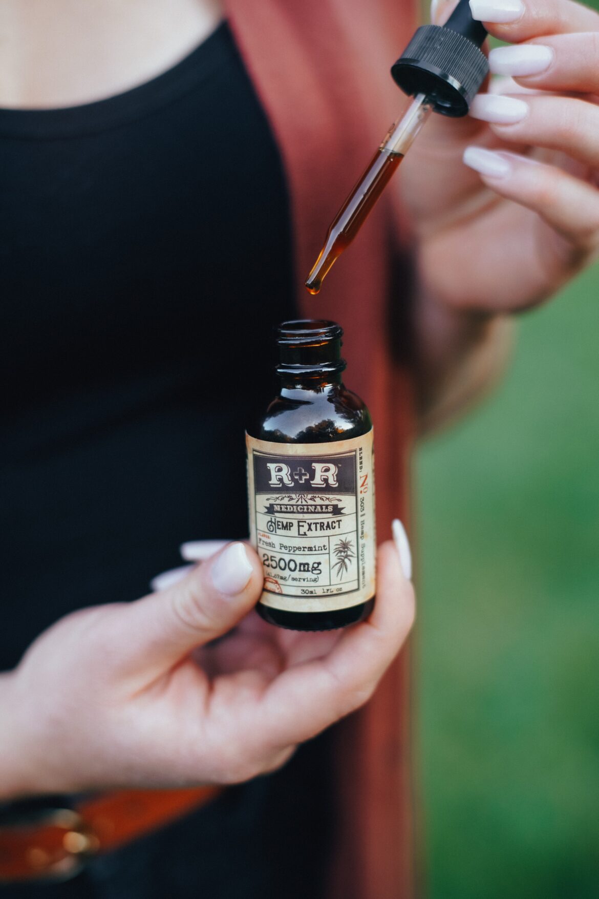 A lady holding cbd oil dropper - HealthMed.org